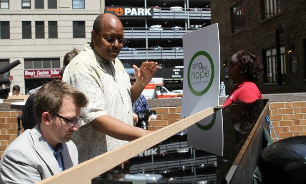 Pianist Brian Neff plays while New York City Housing Authority Youth Chorus director Larry Matthew conducts and turns pages.